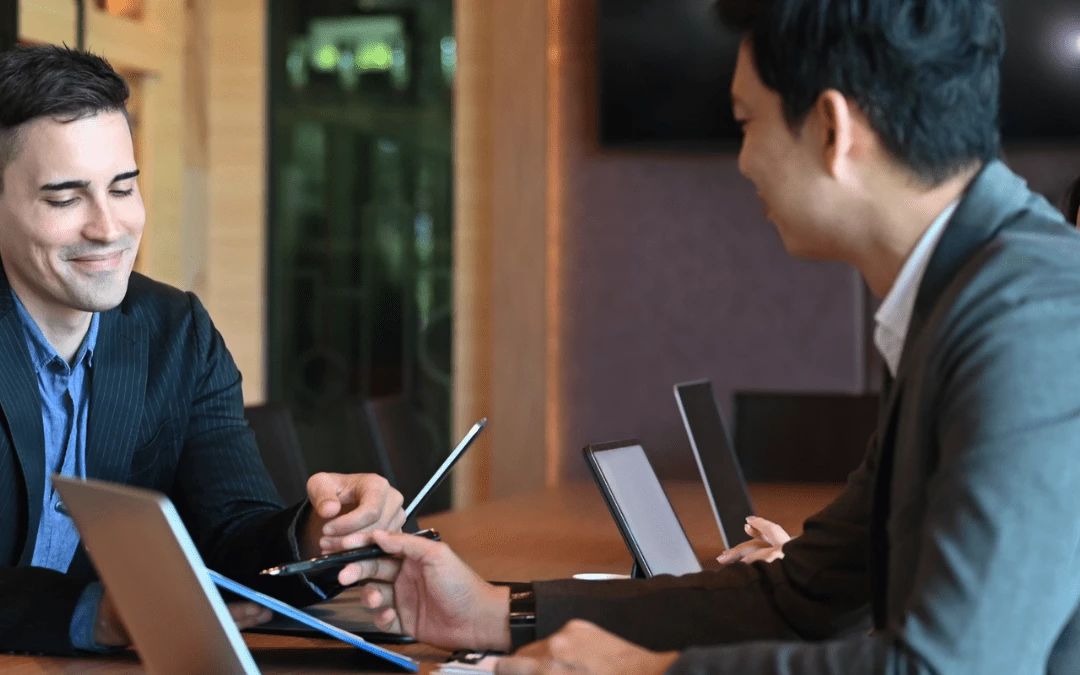 Two Businessman Discussing And Pointing At Tablet Together In Office Meeting Room