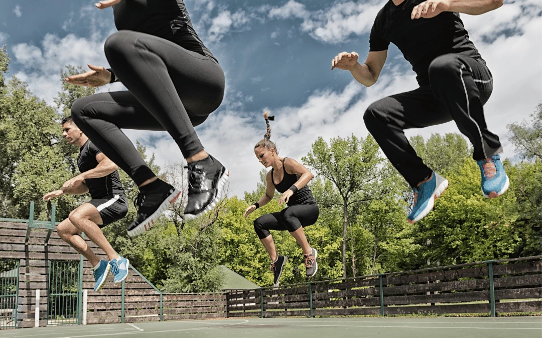 A Group Of Athletic Men And Women Jumping Doing Workout Together At The Park
