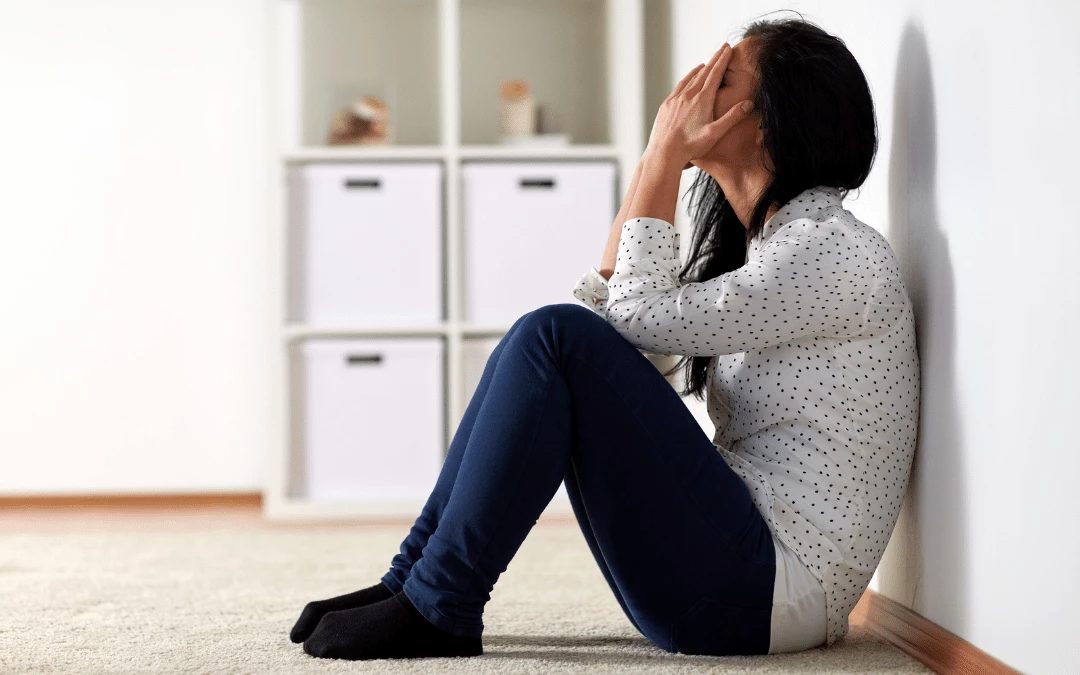 woman-covering-her-face-with-both-her-hand-feeling-stress-sitting-on-the-floor-in-a-house-background