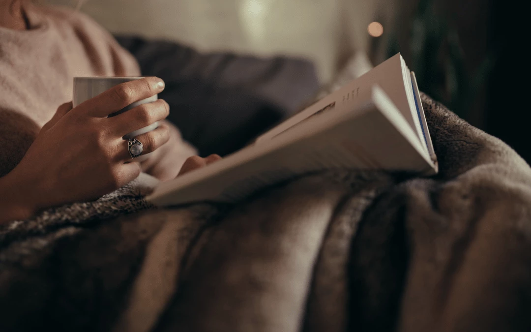 closeup-of-a-woman-holding-a-cup-of-water-on-hand-while-reading-a-book-on-bed-during-nighttime